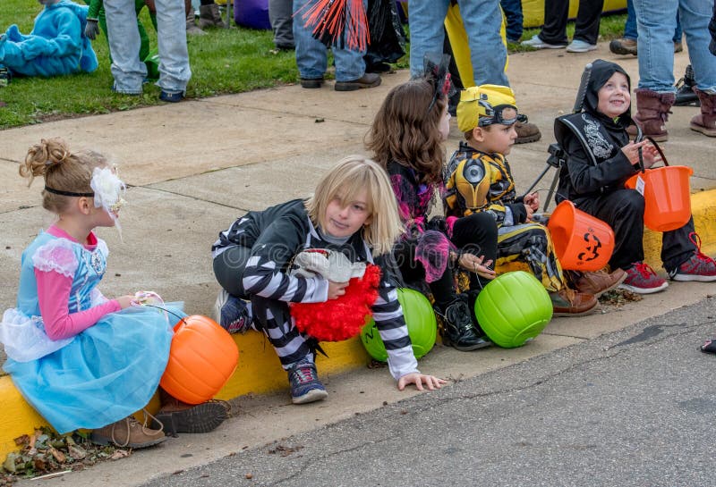 A Row of Children Dressed in Fun Halloween Costumes, Sit on a Curb ...