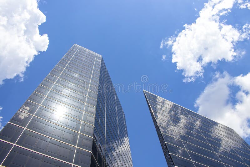 Reflections of sky and clouds on tall modern skyscrapers looking up with lens flare. Reflections of sky and clouds on tall modern skyscrapers looking up with lens flare