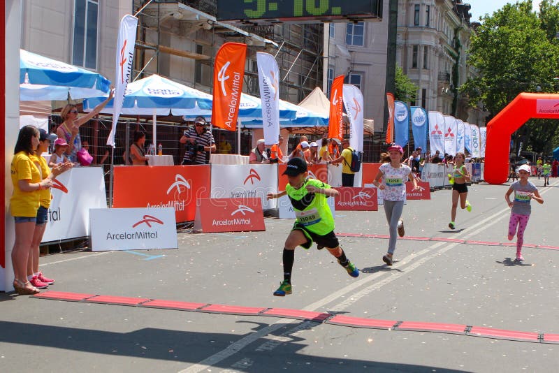 Marathon runners kids cross finish line at sunny summer day