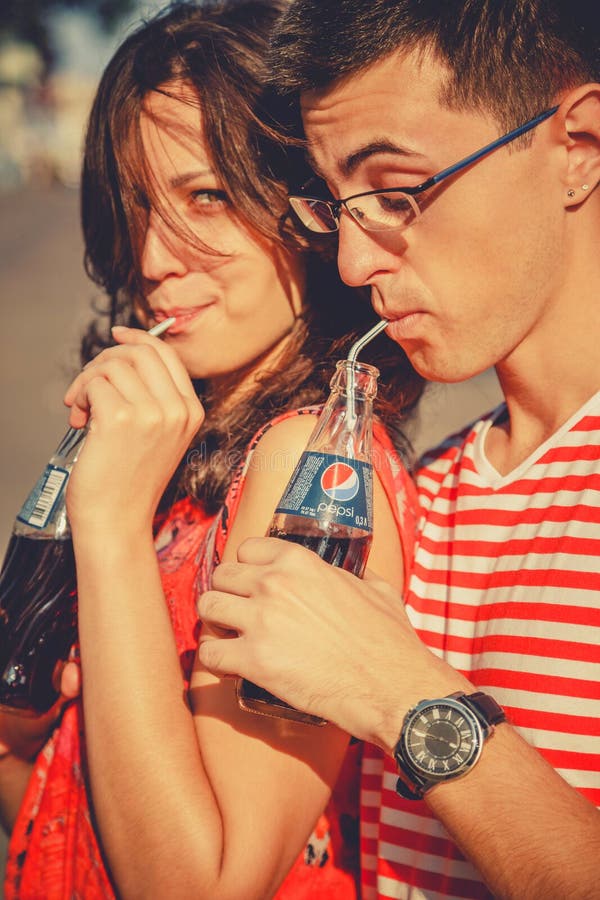 ODESSA, UKRAINE - OCTOBER 15, 2014: Close up of young happy teenage couple outdoors drinking cold Pepsi from glass bottles with st