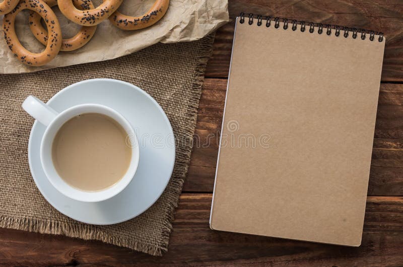 Odgórnego widoku biurowy miejsce pracy: Ð ¡ ardboard notepad z bagels i kawą na drewnianym stole zdjęcie royalty free Odgórnego widoku biurowy miejsce pracy: Ð ¡ ardboard notepad z bagels i kawą na drewnianym stole zdjęcie royalty free