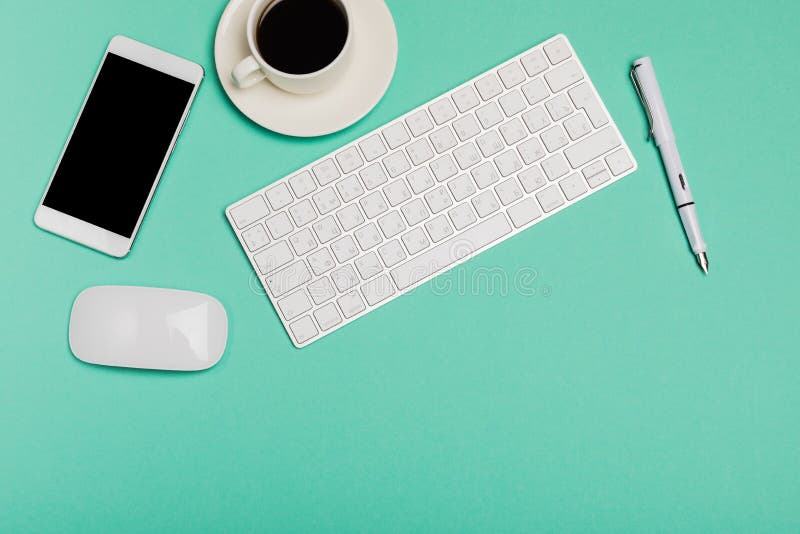 Odgórny widok biurowego biurka workspace z smartphone, klawiaturą, kawą i myszą na błękitnym tle z kopii przestrzenią, projektant fotografia stock Odgórny widok biurowego biurka workspace z smartphone, klawiaturą, kawą i myszą na błękitnym tle z kopii przestrzenią, projektant fotografia stock