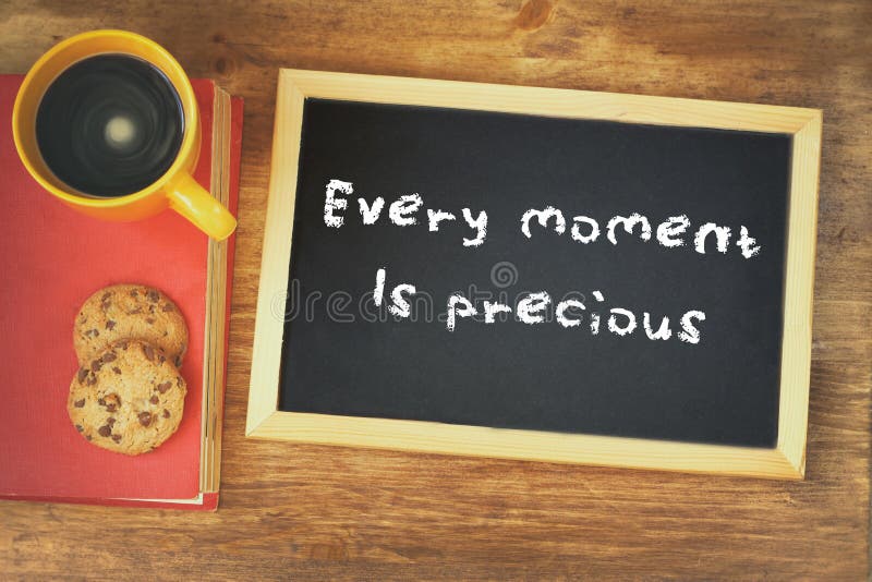 Odgórny widok blackboard z zwrotem każdy moment jest cenny obok filiżanki nad drewnianym stołem obrazy stock Odgórny widok blackboard z zwrotem każdy moment jest cenny obok filiżanki nad drewnianym stołem obrazy stock