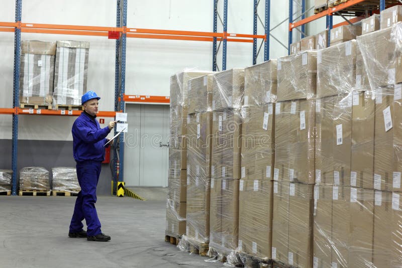 Worker in blue uniform counting stocks in warehouse. Worker in blue uniform counting stocks in warehouse