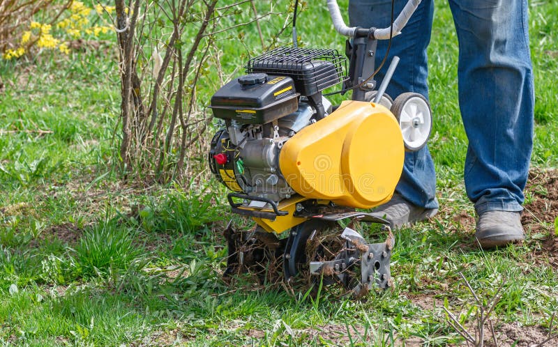 Odling för jordbearbetning i trädgården,motorodling Man Farmer plundrar marken med en odlare arkivfoto Odling för jordbearbetning i trädgården,motorodling Man Farmer plundrar marken med en odlare arkivfoto