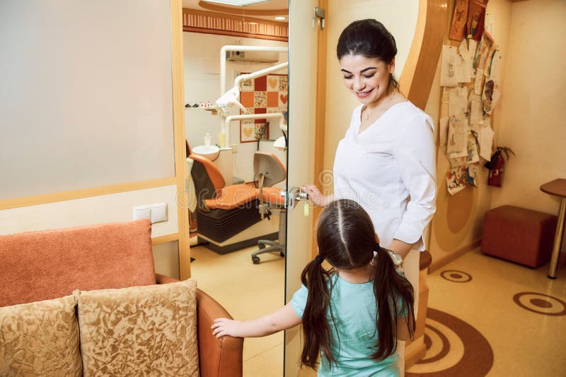 Odontoiatria pediatrica Il dentista invita la ragazza all'ufficio immagini stock libere da diritti Odontoiatria pediatrica Il dentista invita la ragazza all'ufficio immagini stock libere da diritti