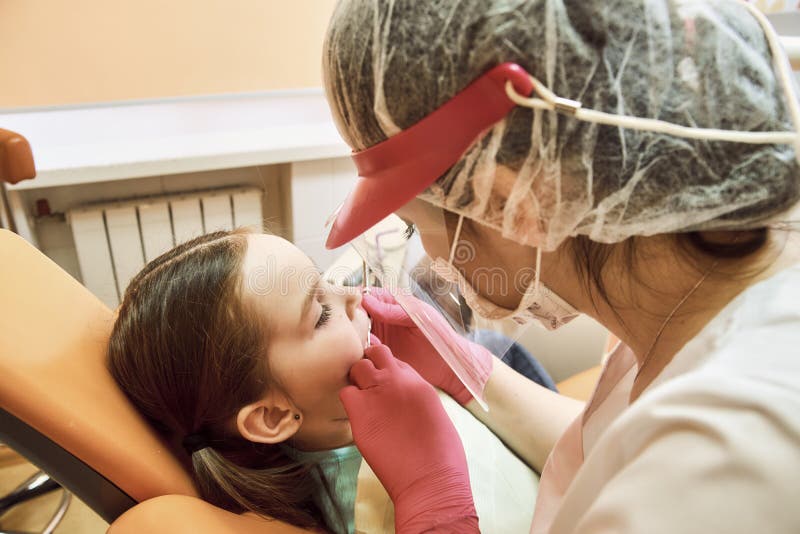 Odontoiatria pediatrica Il dentista tratta i denti della bambina immagini stock Odontoiatria pediatrica Il dentista tratta i denti della bambina immagini stock