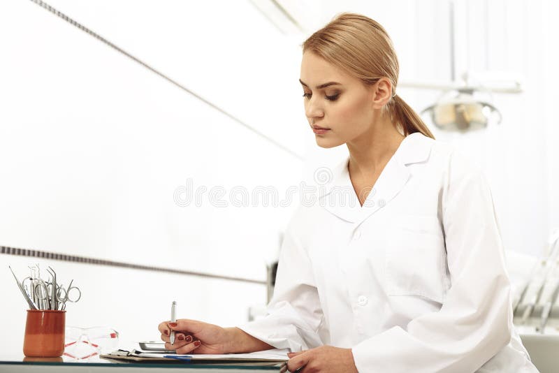 Odontologist filling up a form in office