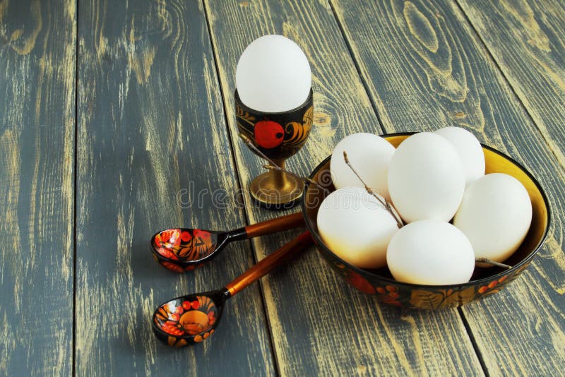 Oeuf blanc dans le support en bois, oeufs dans le plat coloré en bois et cuillères peintes en bois sur le vieux fond en bois appr images stock Oeuf blanc dans le support en bois, oeufs dans le plat coloré en bois et cuillères peintes en bois sur le vieux fond en bois appr images stock