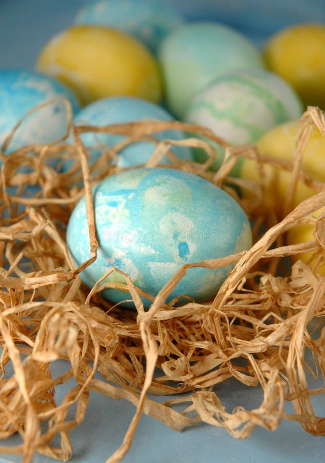 Oeuf bleu dans l'emboîtement de raphia. Un oeuf de pâques bleu dans un petit emboîtement de raphia avec plus d'oeufs derrière.