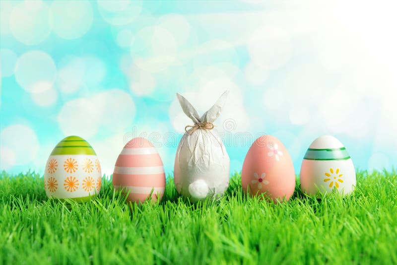Oeuf de pâques enveloppé dans un papier sous forme de lapin avec les oeufs de pâques colorés sur l'herbe verte Concept de vacance photographie stock Oeuf de pâques enveloppé dans un papier sous forme de lapin avec les oeufs de pâques colorés sur l'herbe verte Concept de vacance photographie stock