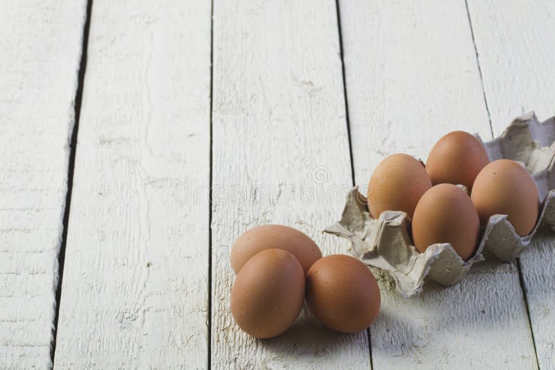 Oeufs dans un plateau de carton sur conseils blancs images libres de droits Oeufs dans un plateau de carton sur conseils blancs images libres de droits