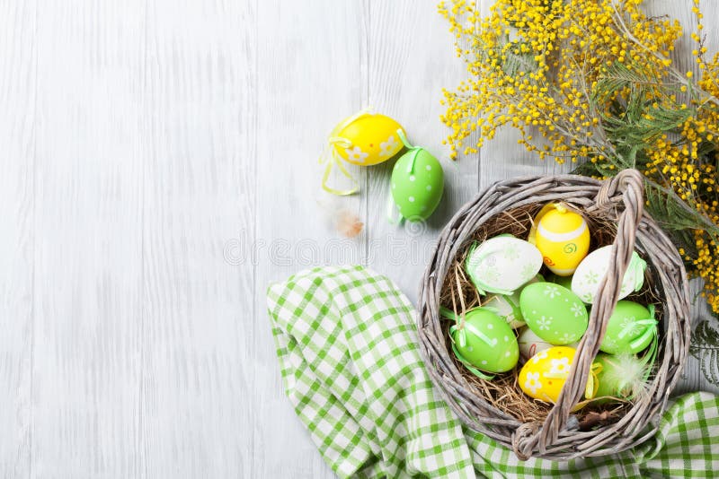 Oeufs de pâques colorés dans le panier et la mimosa image stock Oeufs de pâques colorés dans le panier et la mimosa image stock