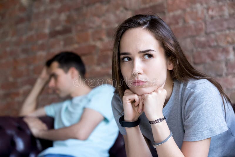 Offended man and woman are seated separately on sofa. royalty free stock photo