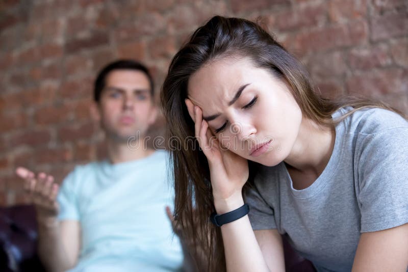 Offended man and woman are seated separately on sofa. royalty free stock photography