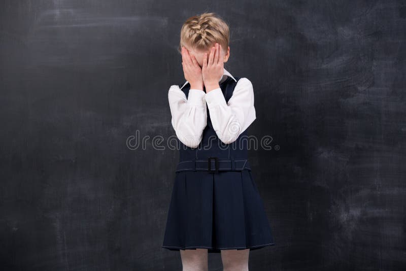 Offended schoolgirl stands at the blackboard