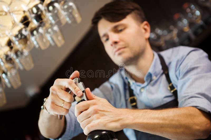 Offene Weinflasche des männlichen Sommelier mit Korkenzieher lizenzfreies stockbild Offene Weinflasche des männlichen Sommelier mit Korkenzieher lizenzfreies stockbild