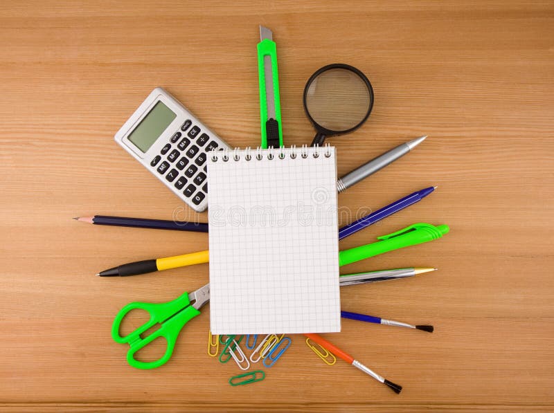 Office accessories under checked notebook on wood