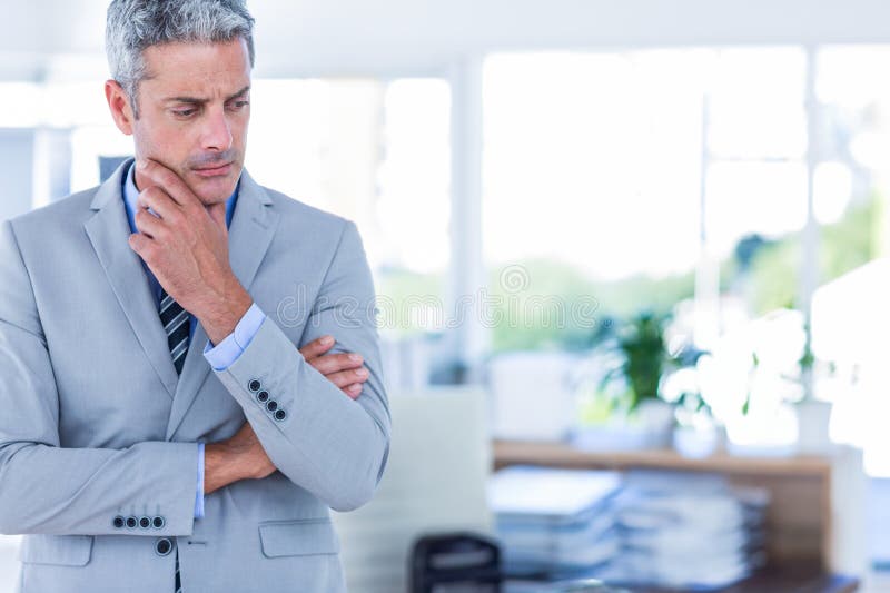 In office, businessman in suit thinking deeply at modern workspace desk, copy space stock photo