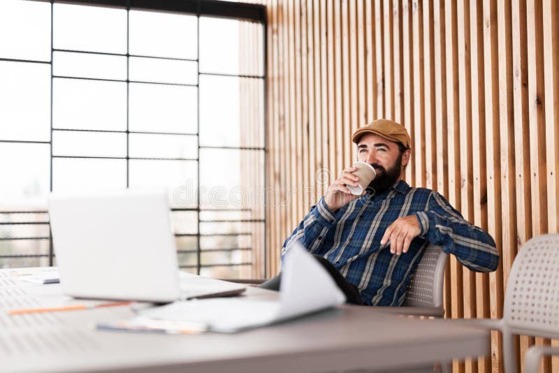 Office-mannen som lättar på kaffekoppen på arbetsplatsen royaltyfri bild Office-mannen som lättar på kaffekoppen på arbetsplatsen royaltyfri bild
