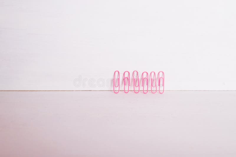 Office supplies.The composition row of multi-colored paper clips on pnk, pastel background.Colorful paper clips isolated