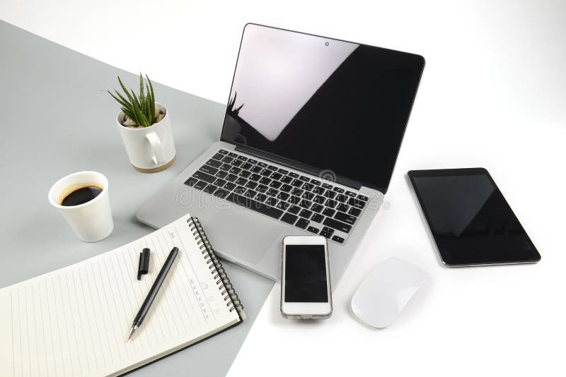 Office table with laptop computer, notebook, digital tablet and smartphone on modern two tone white and grey background royalty free stock images