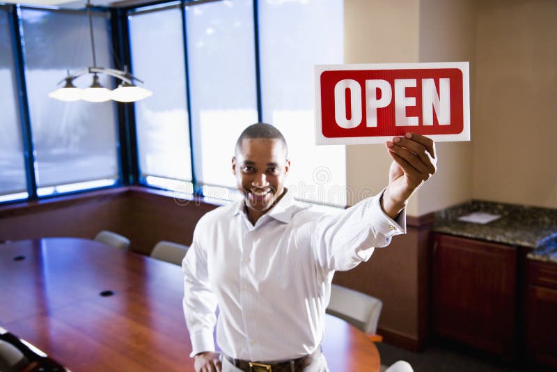 Office worker holding open sign in empty boardroom stock image