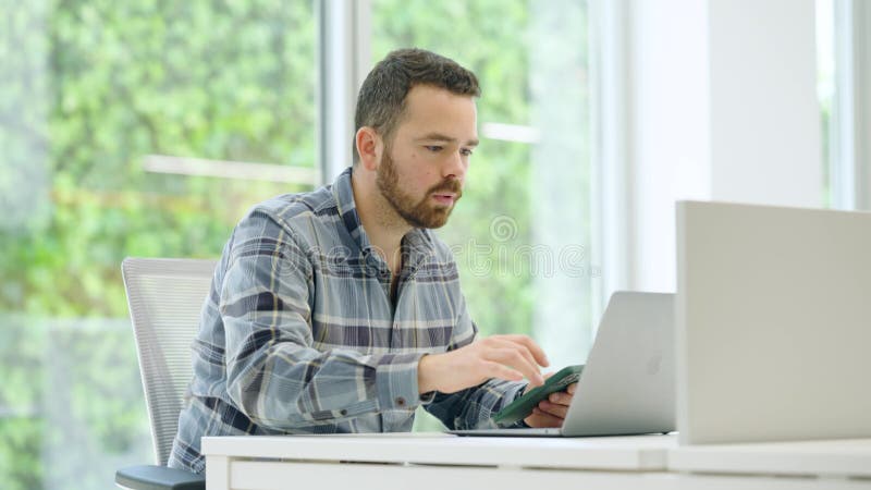Office worker using laptop and smartphone at desk stock video