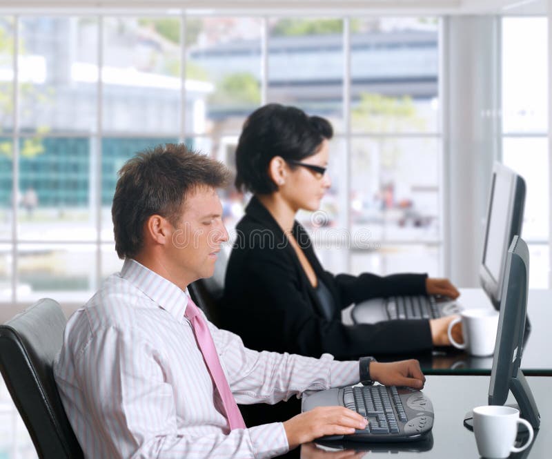 Office workers with computers. Young office workers are sitting in front of their computer screens. Daylight, indoor, office Office workers with computers. Young office workers are sitting in front of their computer screens. Daylight, indoor, office