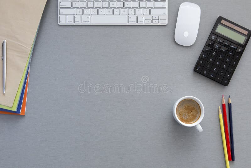 Office working place on grey wooden table Workspace on grey wooden table surrounded with red pen, computer keyboard, booklets and notepad Coffee cup in the middle. Focus is on the coffee surface.