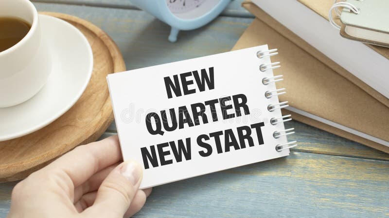 Office workplace with coffee cup, calculator, stationery and plant. Text NEW QUARTER NEW START on white notepad page. royalty free stock image