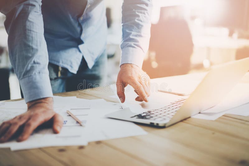 Office world. Businessman working at the wood table with new business project in modern coworking place. Man touching pad contemporary laptop. Horizontal mockup.