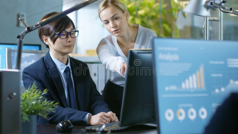 In the Office Young Businesswoman Sitting at Her Desk Talks with stock photo In the Office Young Businesswoman Sitting at Her Desk Talks with stock photo