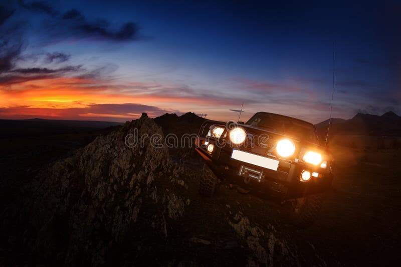 Offroad car on mountain road at sunset