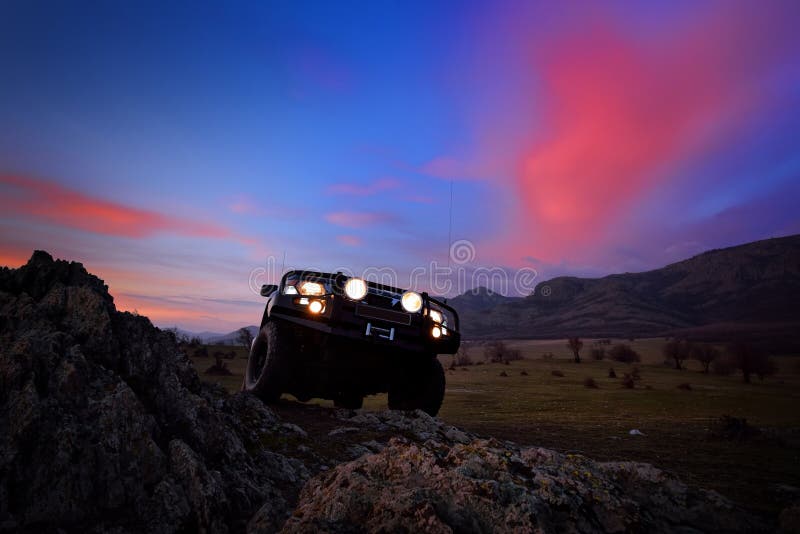 Offroad car on mountain road at sunset