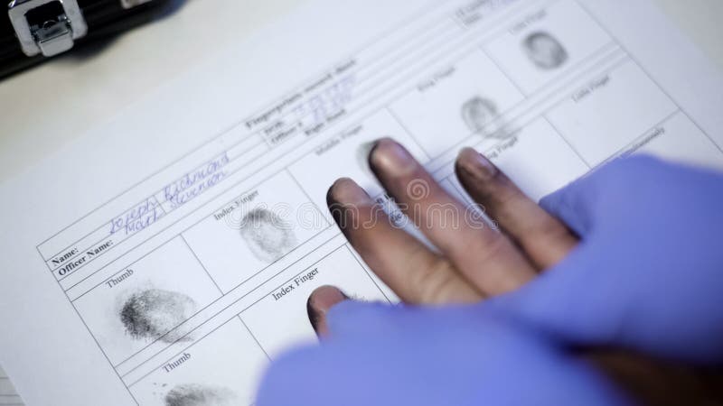 Oficial de policía en los guantes del examen que toman huellas dactilares del sospechoso, primer de las manos fotografía de archivo Oficial de policía en los guantes del examen que toman huellas dactilares del sospechoso, primer de las manos fotografía de archivo