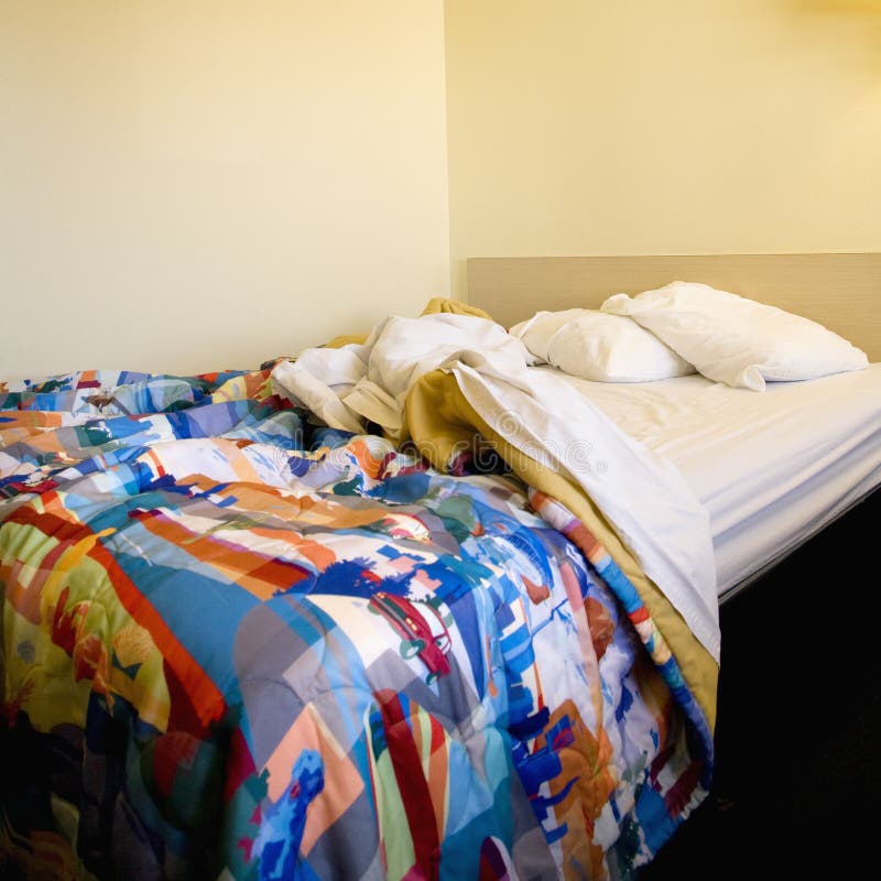 Interior shot of motel room with messy unmade bed. Interior shot of motel room with messy unmade bed.