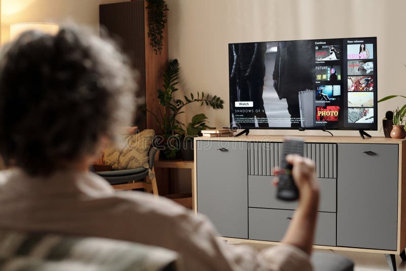 Oglądanie telewizji i utrzymywanie zdalnego sterowania w domu obraz stock