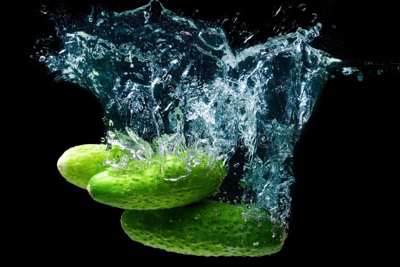 Group of fresh cucumbers dropped in water with splashes isolated on black background. Group of fresh cucumbers dropped in water with splashes isolated on black background