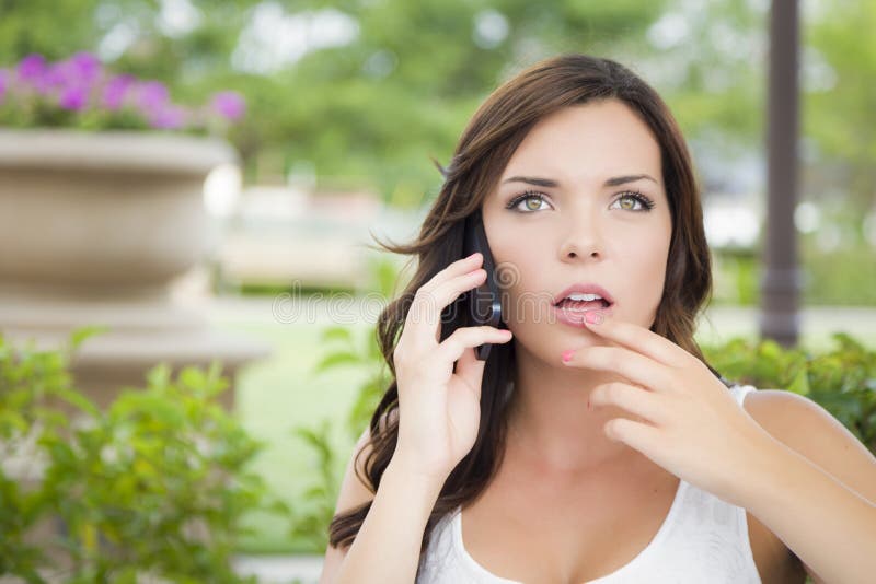 Ogłuszona Młoda Dorosła kobieta Opowiada na telefonie komórkowym Outdoors obrazy royalty free Ogłuszona Młoda Dorosła kobieta Opowiada na telefonie komórkowym Outdoors obrazy royalty free
