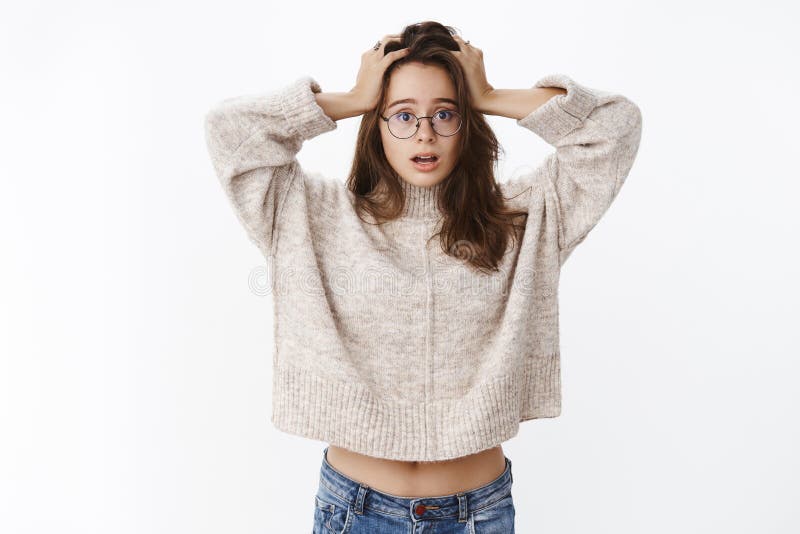 Oh my, what to do. Silly and clueless good-looking confused girl in glasses and sweater holding hands on head, open royalty free stock image Oh my, what to do. Silly and clueless good-looking confused girl in glasses and sweater holding hands on head, open royalty free stock image