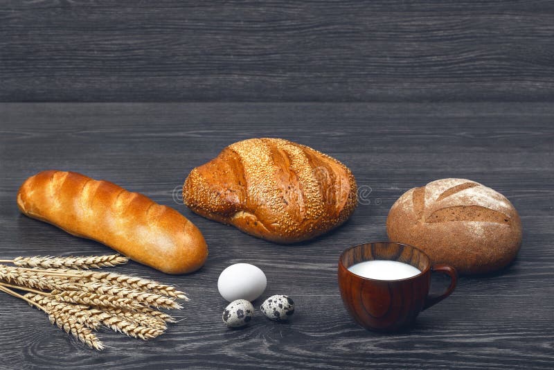 Ohren von Weizen-, Hühner- und Wachteleiern, Glas Milch, backten frisch Brot und ein Laib auf hölzernem Hintergrund stockfotografie Ohren von Weizen-, Hühner- und Wachteleiern, Glas Milch, backten frisch Brot und ein Laib auf hölzernem Hintergrund stockfotografie