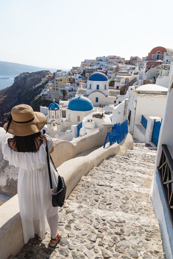 Female tourist with white dress viewing the Greek village with blue dome church, Oia, Santorini, Greece royalty free stock photo Female tourist with white dress viewing the Greek village with blue dome church, Oia, Santorini, Greece royalty free stock photo