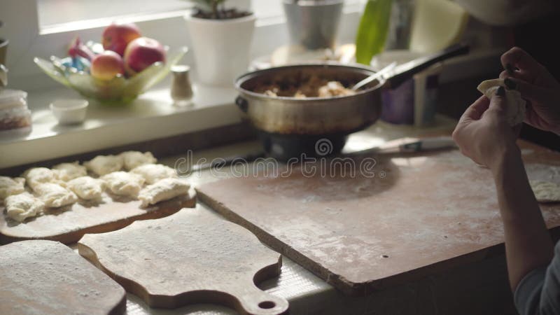 Oigenkännliga unga kaukasiska kvinnor som skulpterar dumplag och som placerar dem på trästyckskivor i köksbord stock video