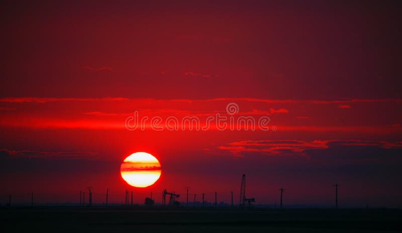 Oil field profiled on solar disc at sunset