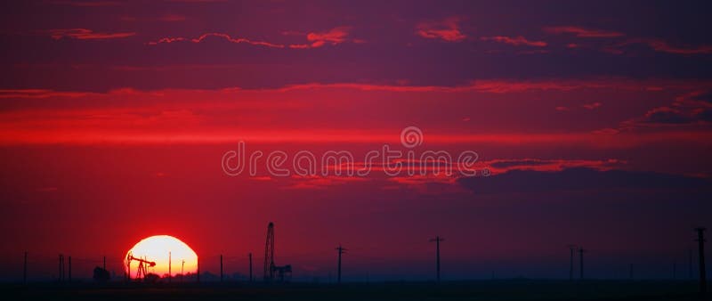 Oil field profiled on solar disc at sunset