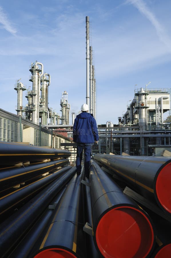 Ingegnere in piedi su tubi di sorveglianza di petrolio e gas di raffineria.