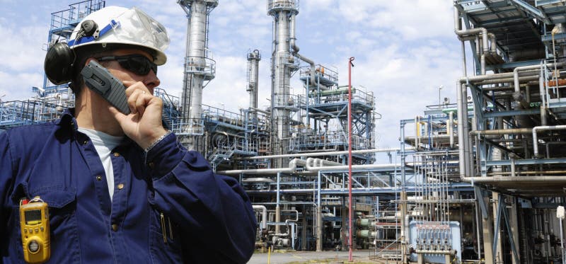 Ingegnere parlando a telefono all'interno di grandi petrolio e di gas industriali della raffineria, panoramica prospettiva.