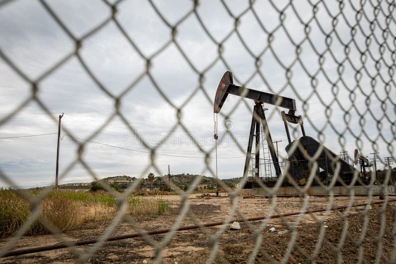 Oil Pump in Cloudy Rough Weather with Chain Link Fence Stock Image