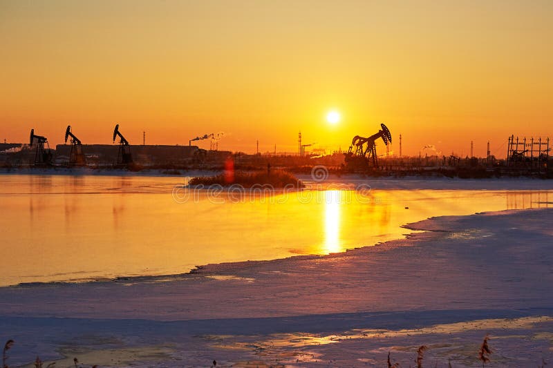 The oil pumping on the lakeside sunrise